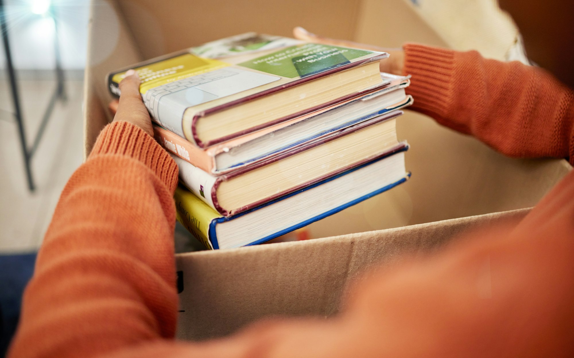 Donation, charity and woman hands with books in box for nonprofit and cardboard container at home.